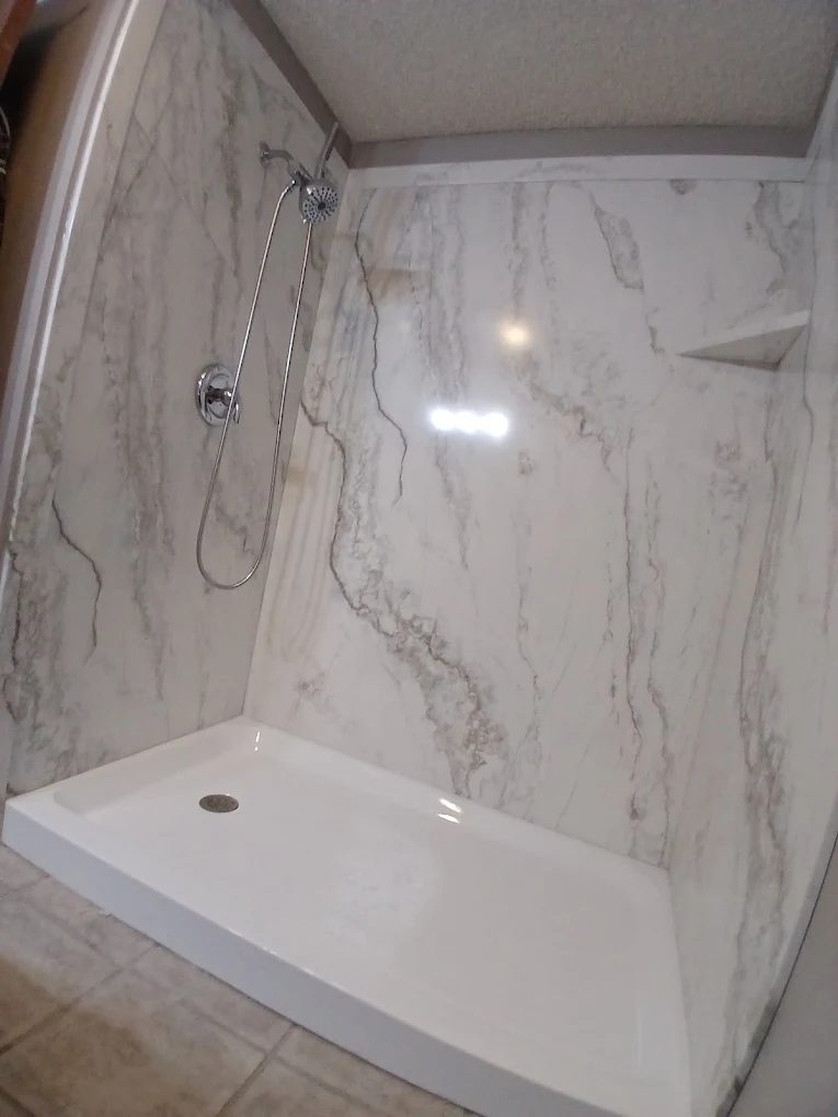 Modern marble shower enclosure with white base and gray veining on walls