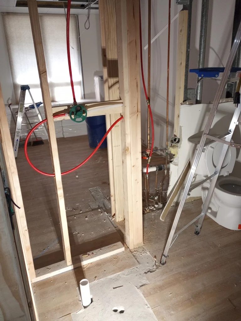 Under-construction bathroom framed with wooden studs and red electrical wiring
